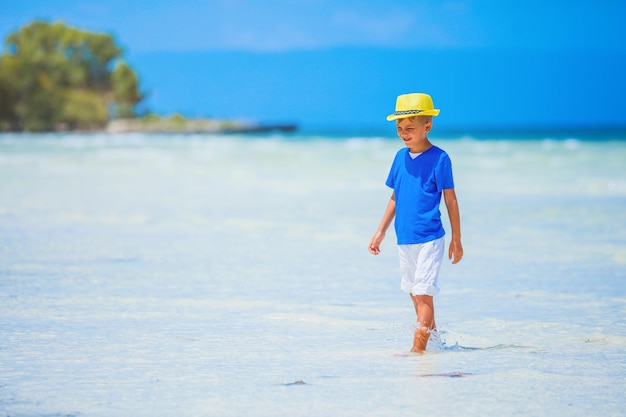 Netter kleiner Junge mit gelbem Hut, der sich am Meeresstrand amüsiert