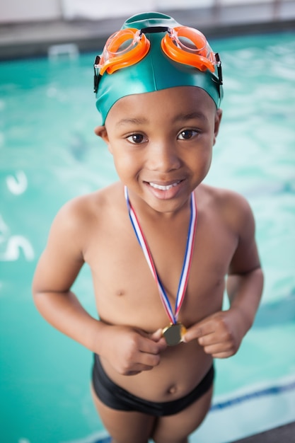 Netter kleiner Junge mit seiner Medaille am Pool