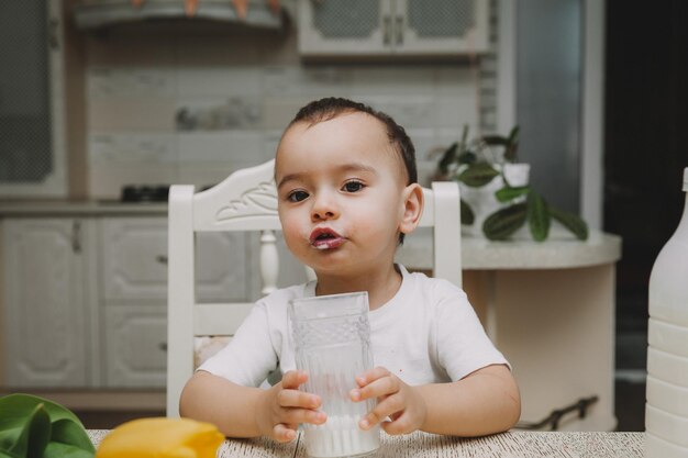 Netter kleiner junge trinkt milch am tisch in der küche milchflasche mocap