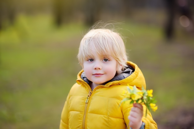 Netter kleiner Junge wählen wilde Blumen im Park aus