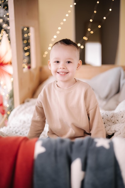 Netter kleiner Junge zu Hause während der Winterferien Weihnachtsbaum und viele Geschenke