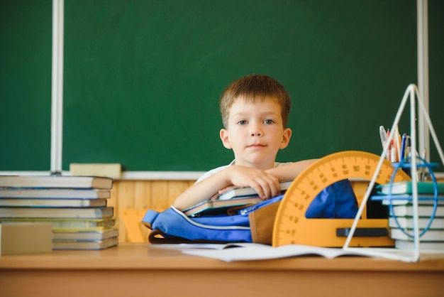 Netter kleiner Schuljunge, der im Klassenzimmer sitzt