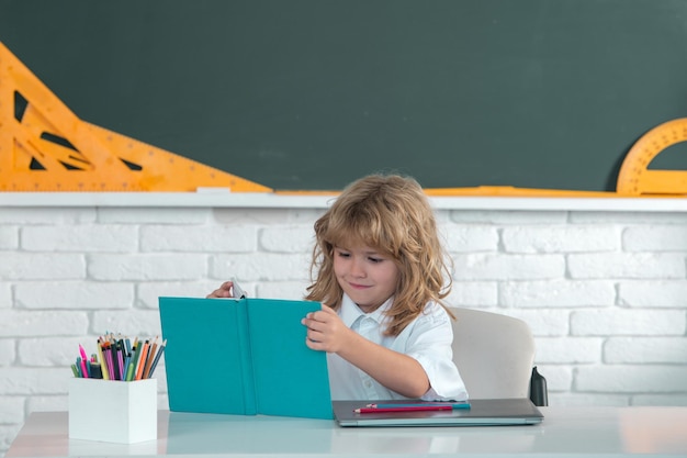 Netter kleiner Schuljunge las Buch in einem Klassenzimmer