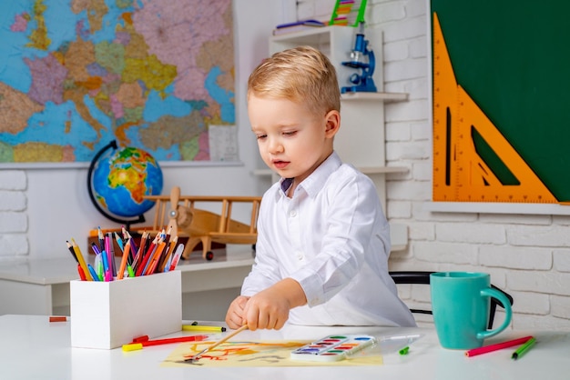 Netter kleiner Vorschuljunge mit Lehrerstudium in einer Klassenzimmer-Grundschule und Bildung nachher