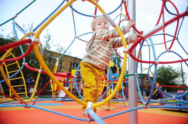 Netter Kleinkindjunge, der Spaß auf Spielplatz hat. Aktiv im Freien Spiel für kleine Kinder