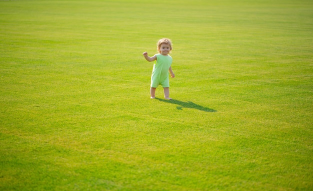 Netter lustiger Babyjunge, der lernt, Schritt zu kriechen und Spaß beim Spielen auf dem Rasen im Garten hat