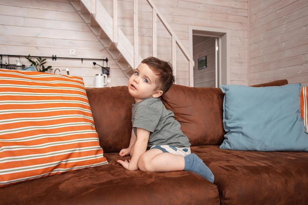 Foto netter lustiger kleiner kleinkindjunge, der kamera lächelndes kind betrachtet, das für porträt zu hause auf couch k...