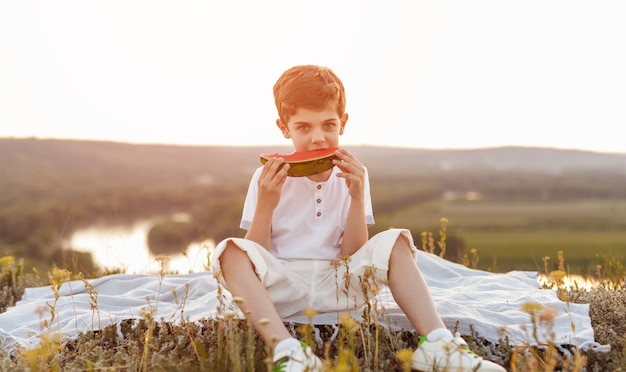 Netter rothaariger Junge, der reife Wassermelone isst