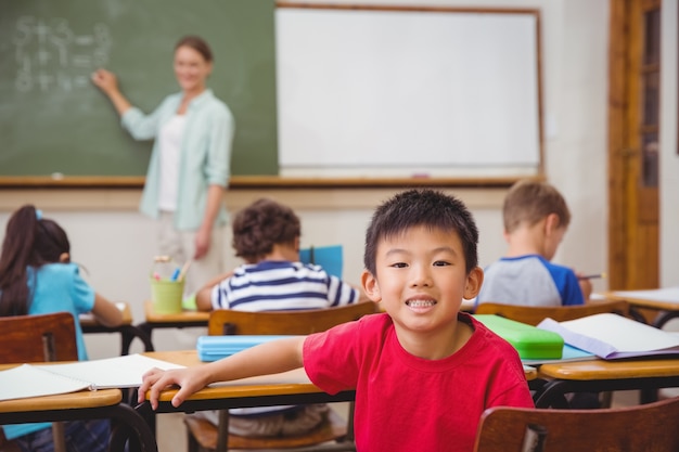 Netter Schüler, der an der Kamera im Klassenzimmer lächelt