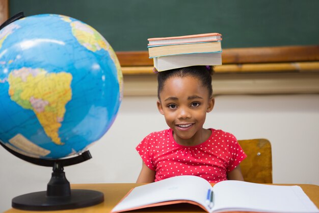 Netter Schüler, der Bücher auf ihrem Kopf hält