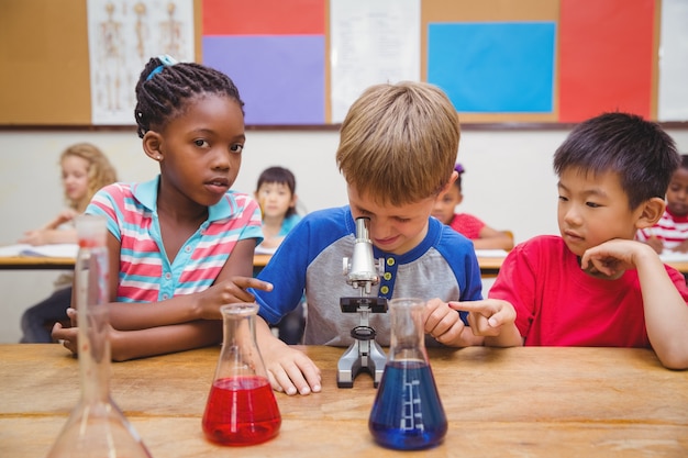 Netter Schüler, der durch Mikroskop schaut