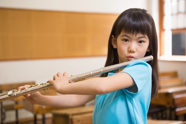 Netter Schüler, der Flöte im Klassenzimmer spielt