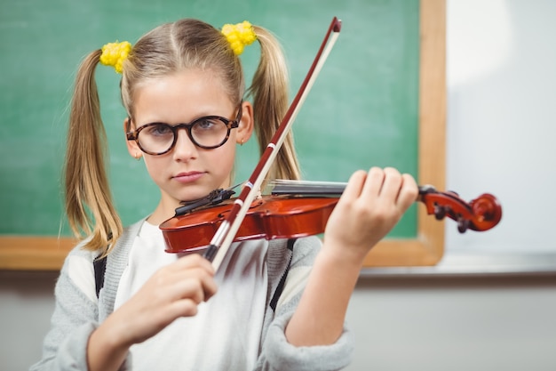 Netter Schüler, der Violine in einem Klassenzimmer spielt