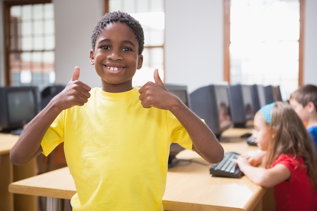 Netter Schüler in der Computerklasse, die an der Kamera lächelt