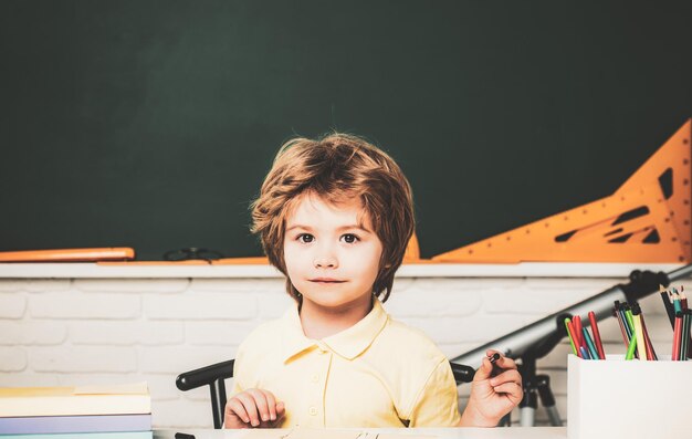 Netter Schüler mit lustigem Gesicht Schularbeit Porträt des Schülers der Grundschulstudie drinnen