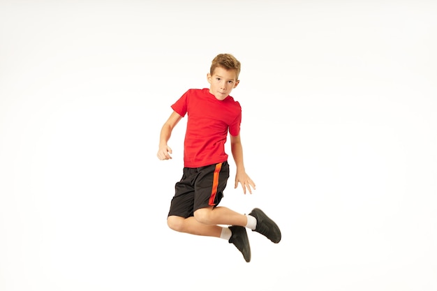 Netter sportlicher Junge in kurzen Hosen, der in die Kamera schaut und im Studio springt. Isoliert auf weißem Hintergrund