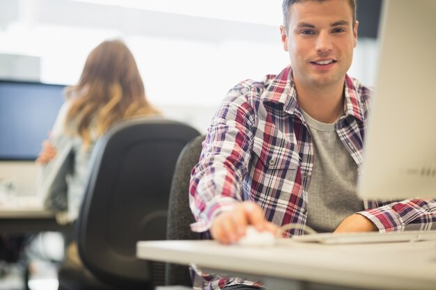 Foto netter student, der kamera im computerraum betrachtet