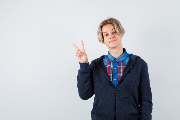 Netter Teenager im Hemd, Hoodie mit V-Zeichen und fröhlichem Aussehen, Vorderansicht.