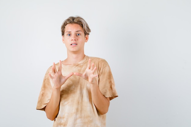 Netter Teenager im T-Shirt, der Kapitulationsgeste zeigt und erschrocken aussieht, Vorderansicht.