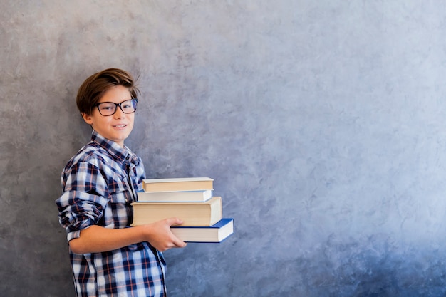 Netter Teenager-Schuljunge, der Bücher hält