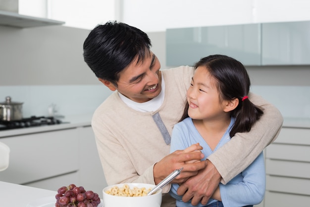 Netter Vater mit der Tochter, die Getreide in der Küche isst