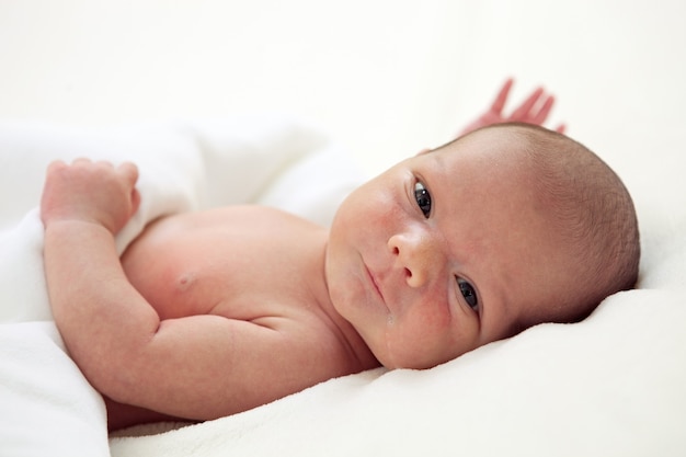 Netter wöchentlicher kleiner Junge bedeckt mit Decke