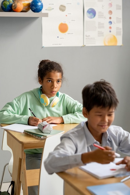 Nettes afroamerikanisches Schulmädchen, das Tafel oder Lehrer betrachtet