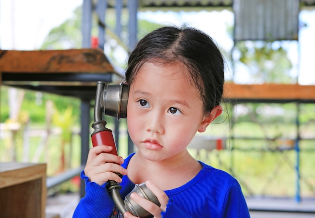 Nettes asiatisches Kindermädchen, das das Retro- Telefon verwendet.