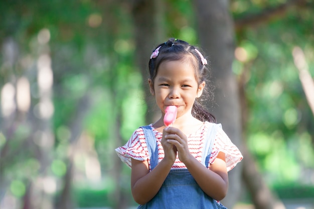 Nettes asiatisches Kindermädchen, das Eiscreme im Park isst