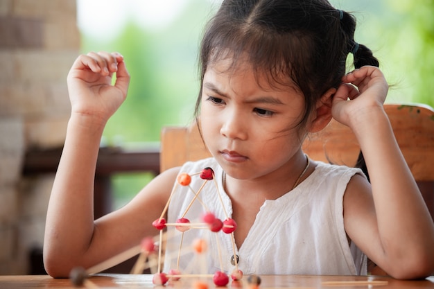 Nettes asiatisches Kindermädchen, das mit Spielteig und -zahnstocher spielt und schafft.