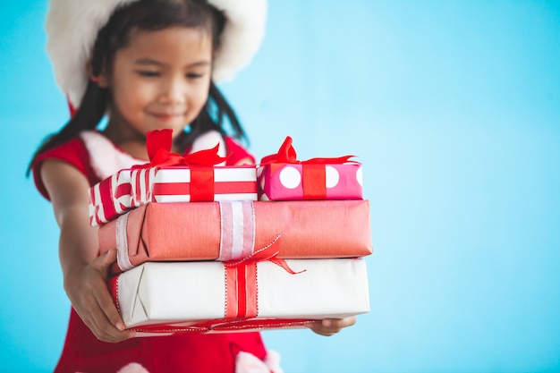 Nettes asiatisches Kindermädchen, das Sankt-Hut trägt und in der Hand schönes Geschenk hält