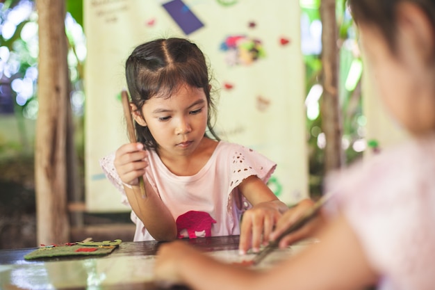 Nettes asiatisches Kindermädchen machen ein Handwerk mit Recyclingpapier vom Hacken der Elefanten