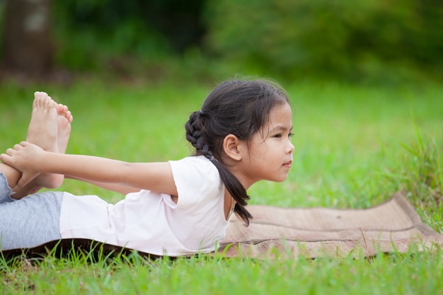 Nettes asiatisches kleines Kindermädchen, das Übung im Park tut