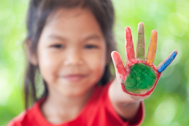 Nettes asiatisches kleines kindermädchen mit den gemalten händen, die finger nr. fünf zeigen