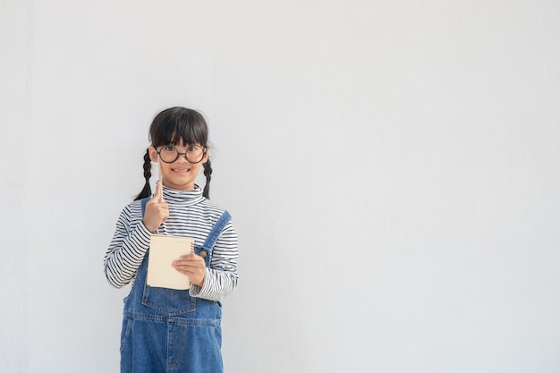 Nettes asiatisches kleines Mädchen mit Brille und Denken