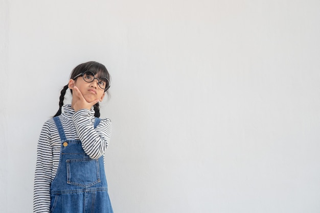 Nettes asiatisches kleines Mädchen mit Brille und Denken