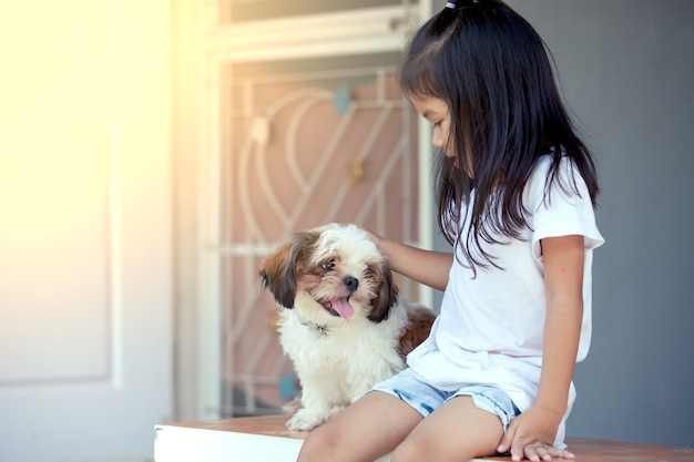 Nettes asiatisches kleines Mädchen mit ihrem Shih Tzu-Hund im Weinlesefarbton