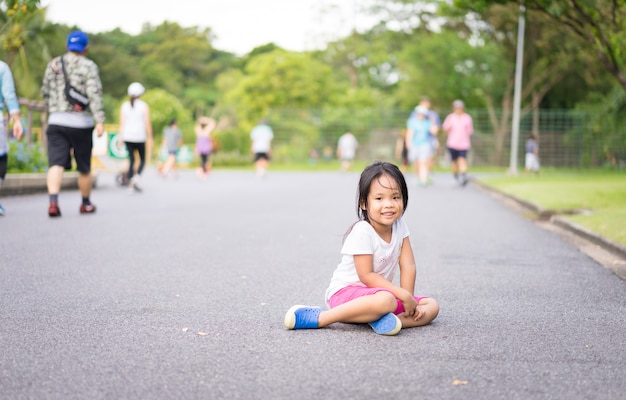 Nettes asiatisches liittle Mädchen, das auf Straße im Park sitzt