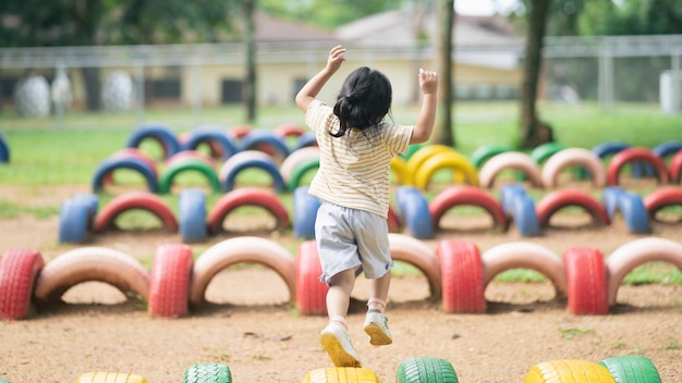 Nettes asiatisches Mädchen lächelt und spielt auf dem Schul- oder Kindergartenhof oder Spielplatz Gesunde Sommeraktivität für Kinder Kleines asiatisches Mädchen, das draußen auf dem Spielplatz klettert Kind spielt auf dem Spielplatz im Freien