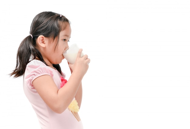 Nettes asiatisches Mädchen, welches die frische Milch lokalisiert trinkt