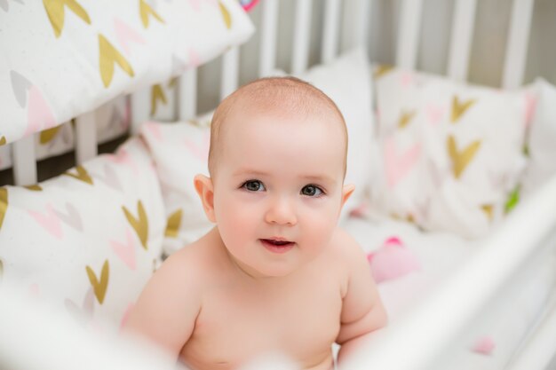 Nettes Baby 8 Monate sitzt im Babybett zu Hause