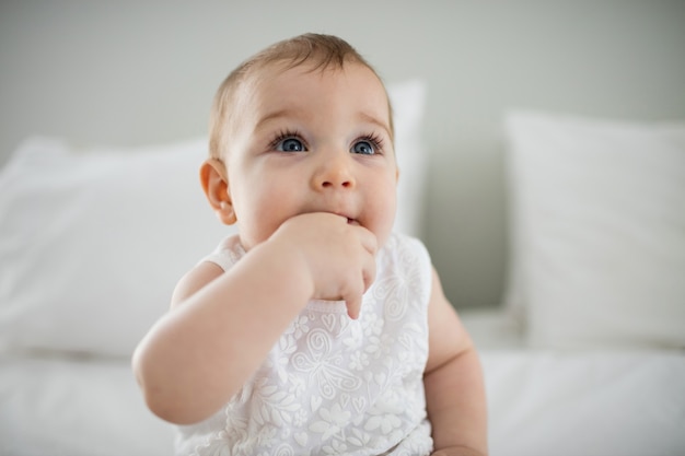 Nettes Baby, das auf Bett im Schlafzimmer entspannt