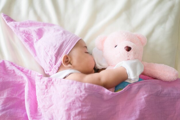 Nettes Baby, das auf Bett legt Neugeborenes schlafend mit Teddybär. Zwei Monate