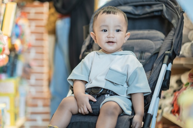 Nettes Baby, das auf einem Kinderwagen im Einkaufszentrum sitzt