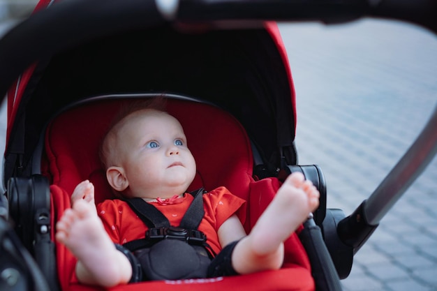 Nettes Baby, das im roten Kinderwagen sitzt