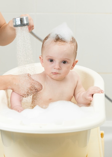 Nettes Baby, das in der Badewanne voller Schaum sitzt