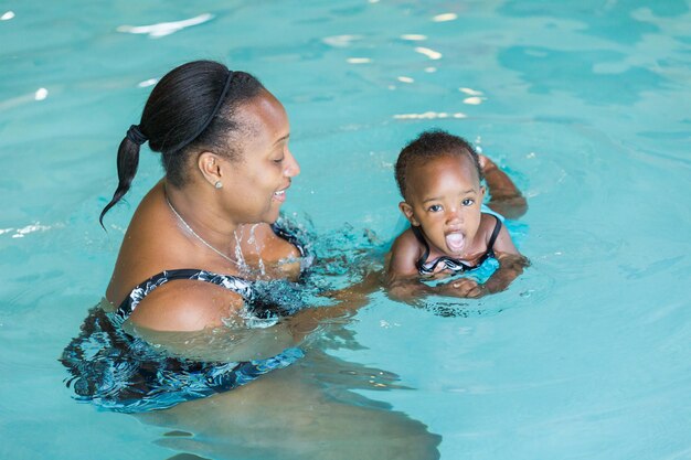 Nettes Baby, das lernt, im Hallenbad zu schwimmen.