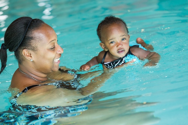 Nettes Baby, das lernt, im Hallenbad zu schwimmen.