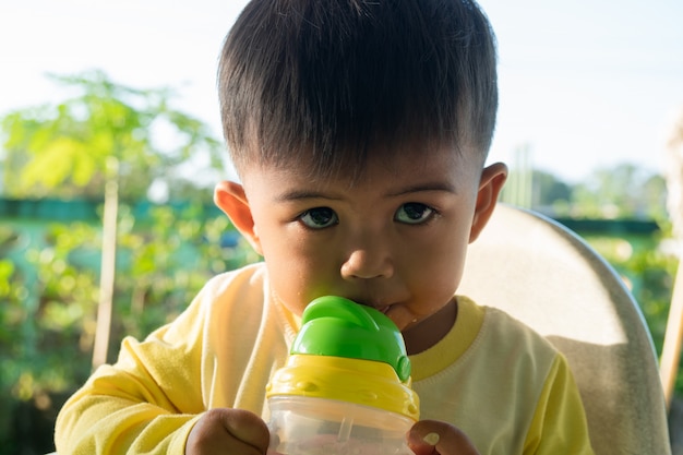 Nettes Baby, das Wasser von den Flaschen saugt