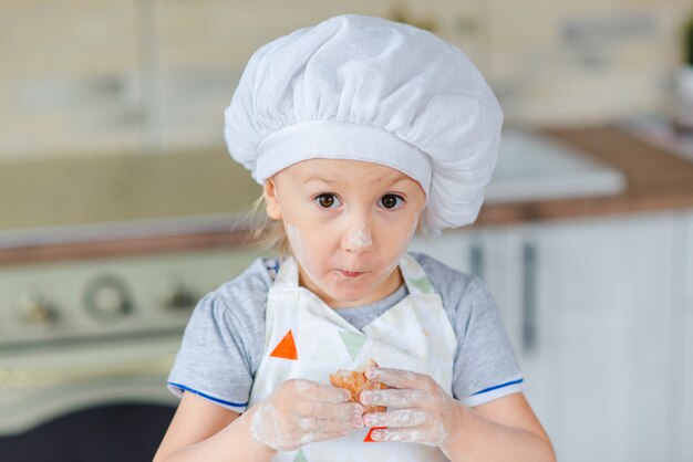 Nettes Baby im Kostüm kocht, das in der Küche kocht